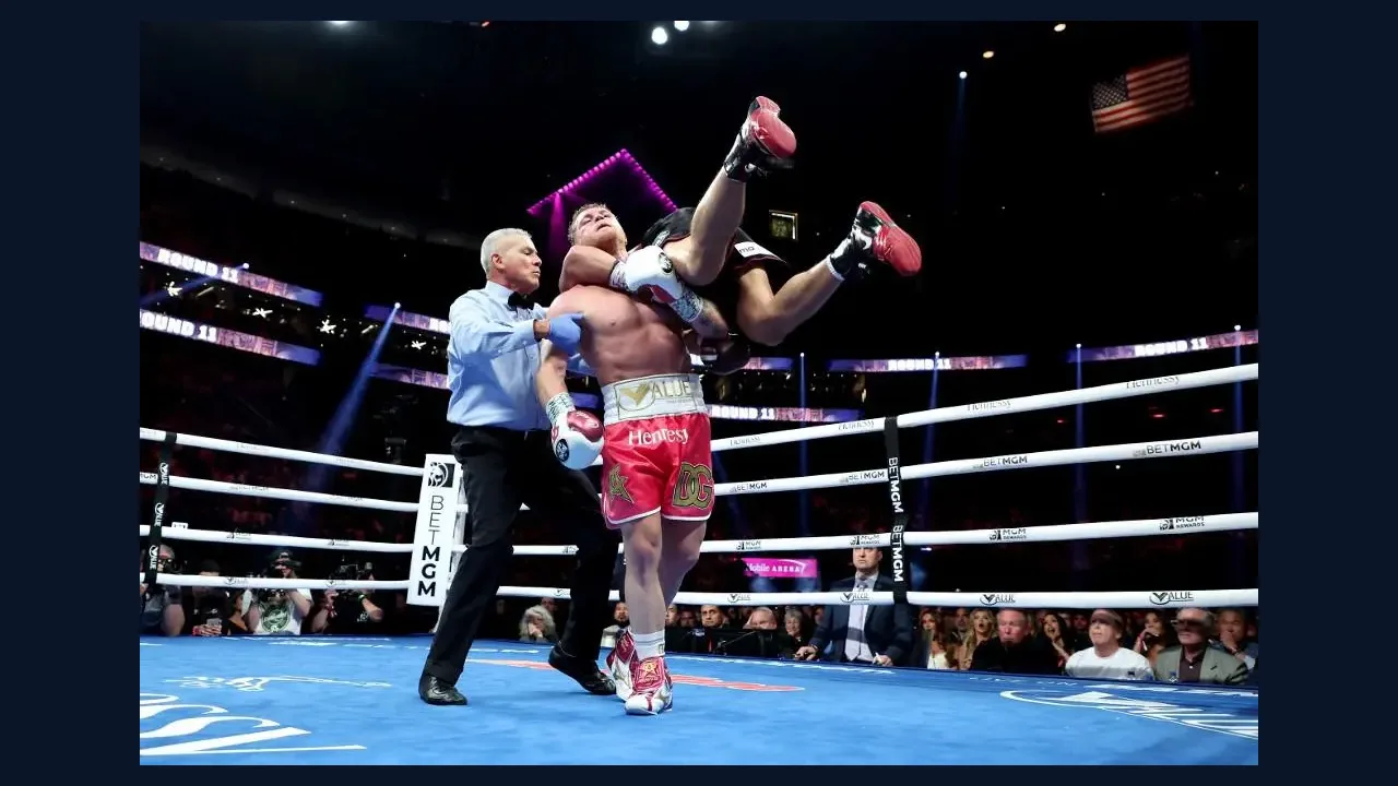 Boxer celebrating a win in the ring as the referee steps in