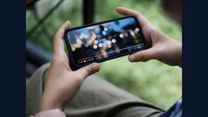 Hands holding a phone playing a video outdoors